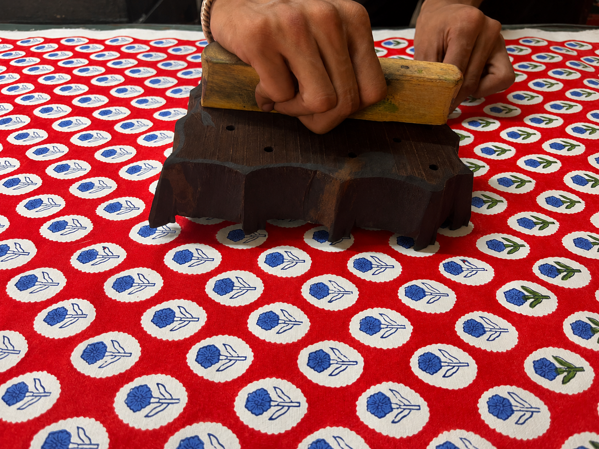 Artisan hand block printing a red floral textile